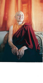 Elderly person in maroon and orange robe.