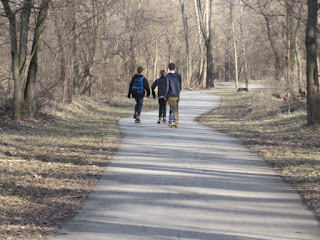 Three people walking on a forest path.