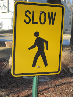 Yellow pedestrian caution sign reading "SLOW".