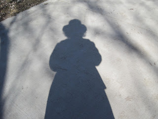 Shadow of person wearing a hat outdoors.