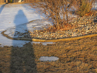 Shadow on snowy and grassy landscape.