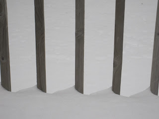 Wooden fence posts in snow-covered ground.