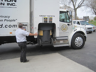 Man loading bin into shredding truck.