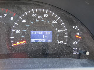 Car dashboard displaying temperature and mileage.