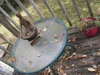 Small statue on round outdoor table.