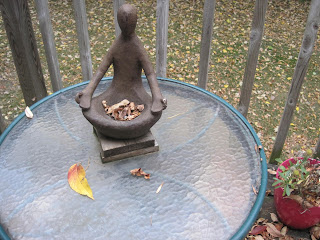 Sculpture on table with fallen leaves.