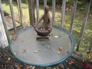Statue on round glass table with leaves.