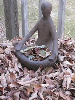 Statue in leaves holding a small bowl.