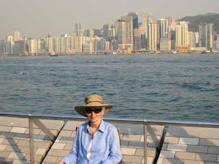 Person sitting by water with city background.