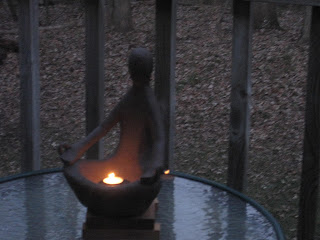 Statue on table with glowing candle.