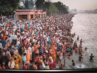 Crowd gathered by riverside for religious event.