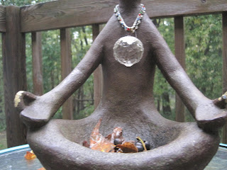 Statue in meditative pose with crystal pendant.