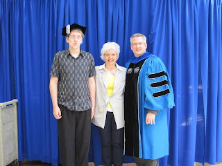 Three people posing in front of curtain.