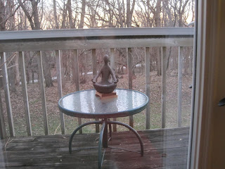 Sculpture on table, wooden deck, winter trees.