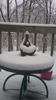 Snow-covered statue on a patio table.