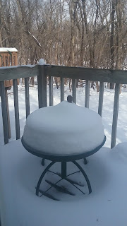 Snow-covered table on a wintery deck.