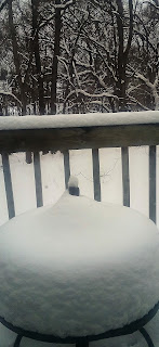 Snow-covered table on a wooden balcony.