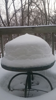 Snow-covered table on a snowy deck.