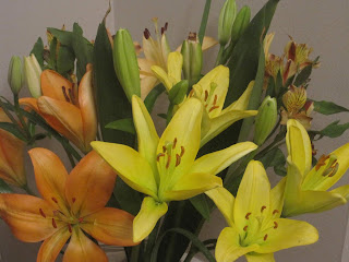 Yellow and orange lilies with green leaves.