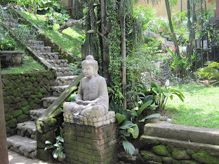Stone Buddha statue in lush garden setting.