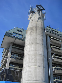 Concrete tower with modern building background.